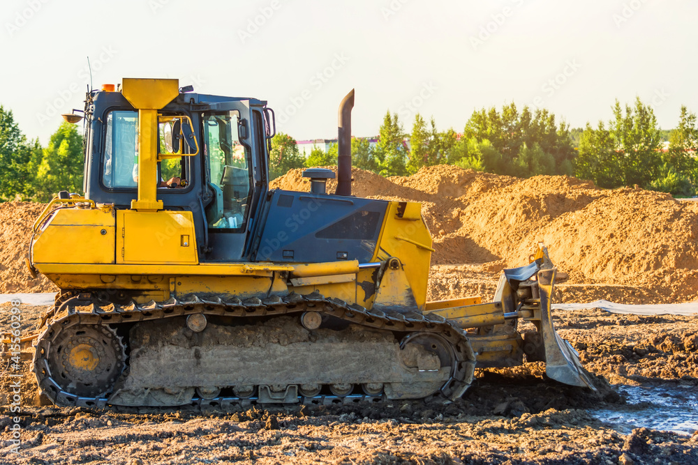 The bulldozer levels the ground during the construction of engineering structures on the ground. The bulldozer levels the ground during the construction of engineering structures on the ground.