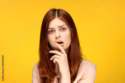 pretty woman attractive look emotions hand near face yellow background