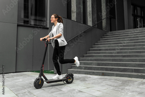 Young woman riding electric scooter in urban background photo