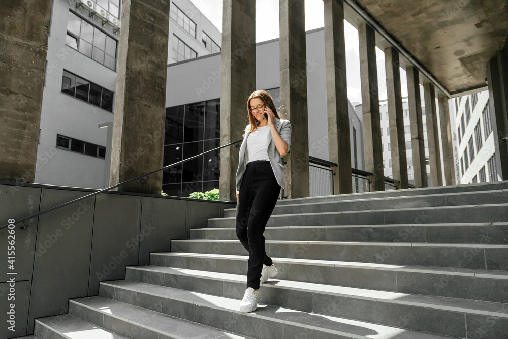 Young woman going downstairs talking on smartphone Young woman going downstairs talking on smartphone