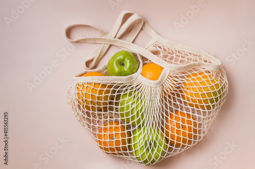 Trendy net shopping string bag with fruit on gray background. Zero waste and plastic free concept. Copy space.