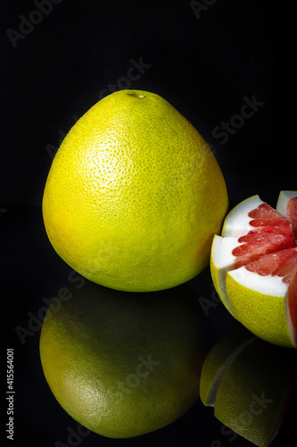 Red pomelo citrus fruit on black background with reflection. Selective focus.