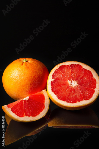 Grapefruit citrus fruit on black background with reflection. Selective focus.