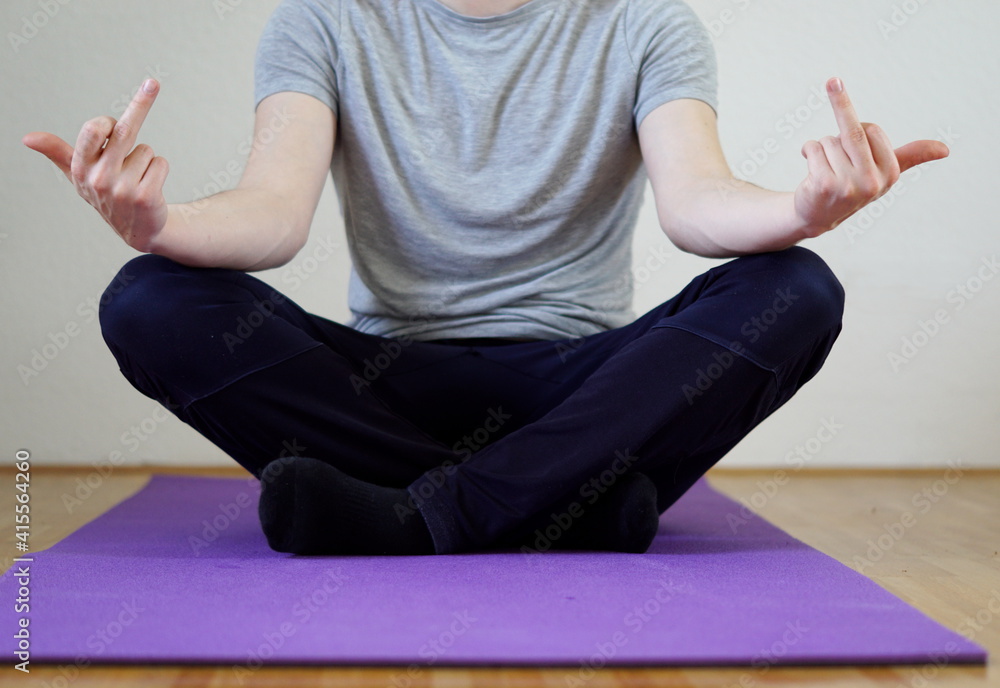 Foto de passive aggressive pose - man sitting in yoga position showing  middle finger do Stock