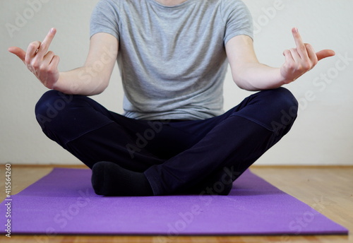 passive aggressive pose - man sitting in yoga position showing middle finger
