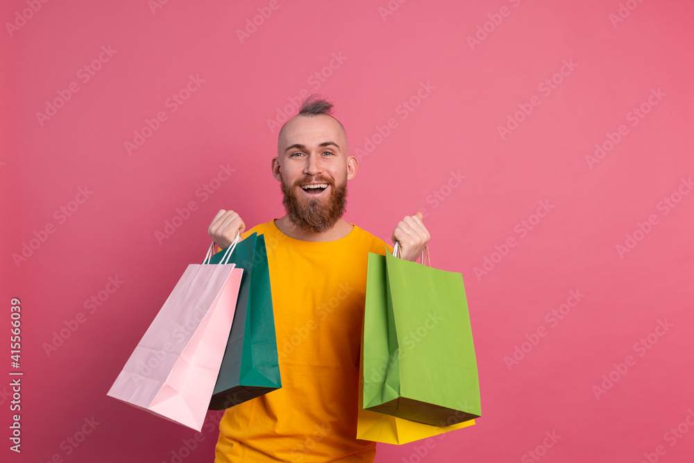 Happy bearded positive man casual look with colorful shopping bags studio pink background Happy bearded positive man casual look with colorful shopping bags studio pink background