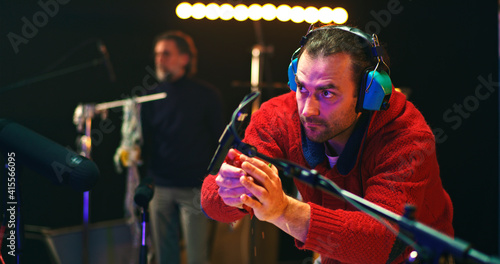 Male colleagues creating various sounds for movie in studio