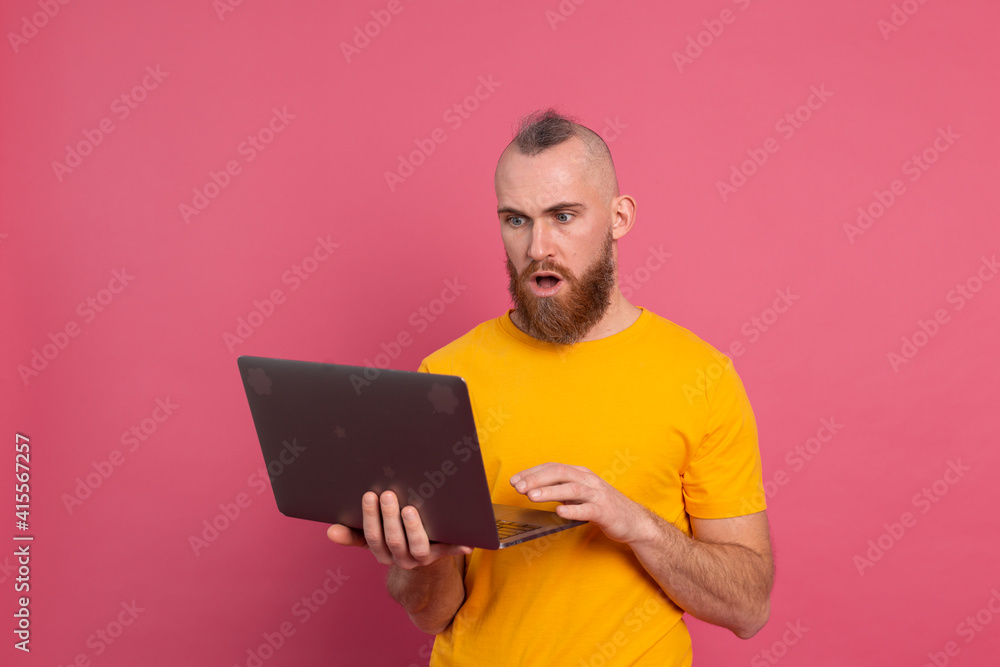 Bearded man with laptop isolated shock emotions on pink background Bearded man with laptop isolated shock emotions on pink background