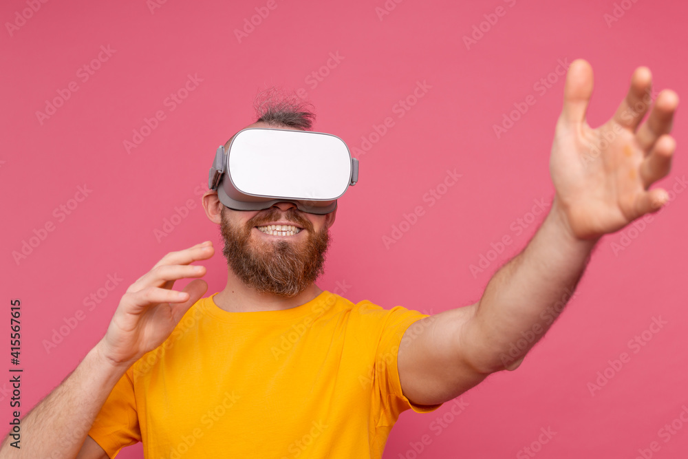 Handsome positive bearded man touching air in vr glasses studio background Handsome positive bearded man touching air in vr glasses studio background