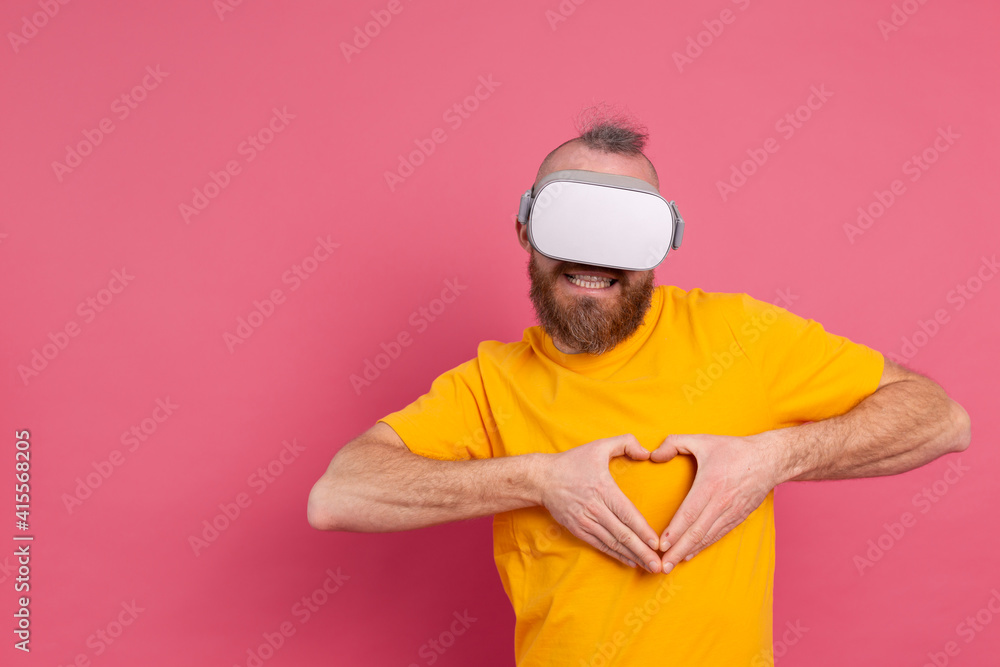 Handsome bearded man in vr glasses shows heart with hands studio background Handsome bearded man in vr glasses shows heart with hands studio background