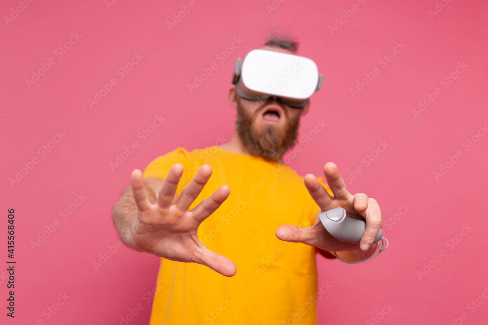 Portrait of scared gamer, man with beard in t-shirt wearing vr glasses on studio background Portrait of scared gamer, man with beard in t-shirt wearing vr glasses on studio background