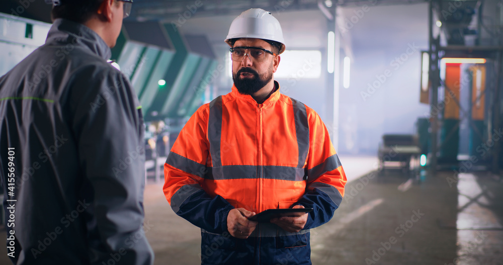 Male inspector speaking with worker on factory Male inspector speaking with worker on factory