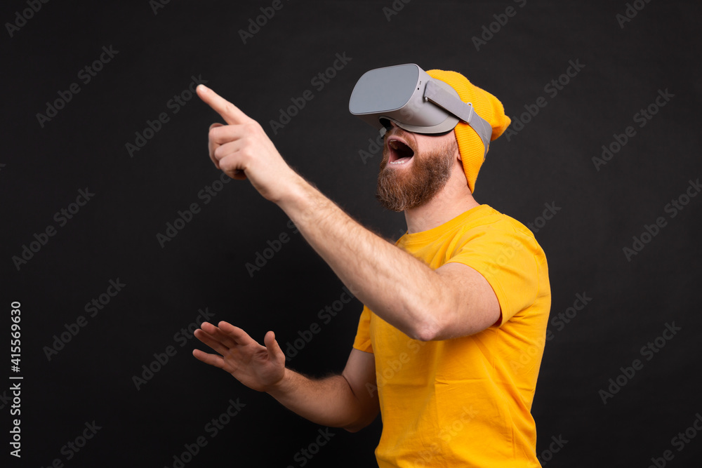Handsome positive bearded man touching air in vr glasses studio background Handsome positive bearded man touching air in vr glasses studio background