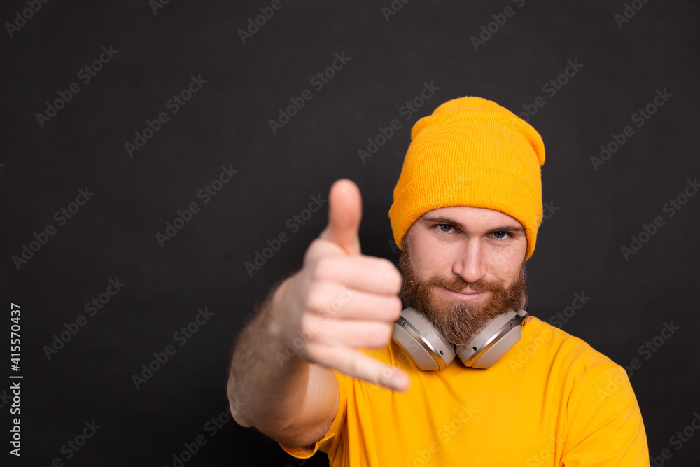Handsome bearded  hipster man yellow hat t shirt with headphones isolated on black  background