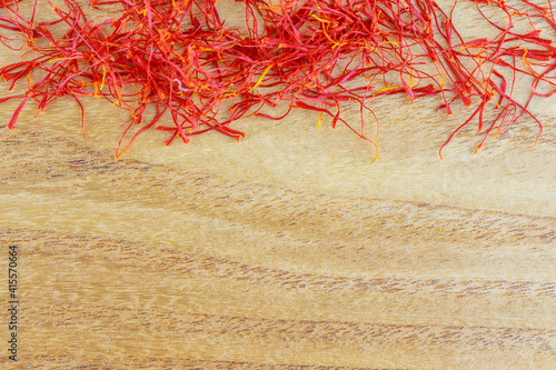 Dry saffron stigmas on a wooden surface. Place for your text. Saffron spice. photo