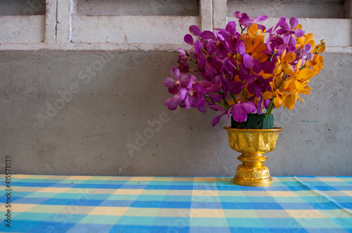 Purple and yellow orchids in a vase on a concrete background.