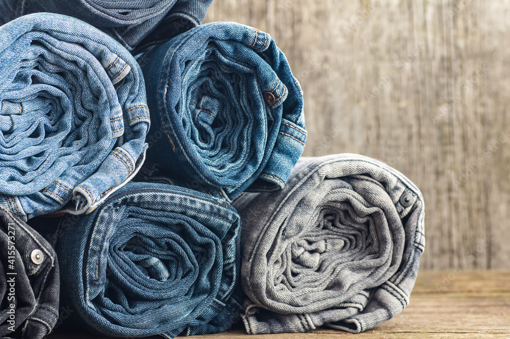 Stack of various denim jeans, trousers on stone wooden rustic background, fashion design Stack of various denim jeans, trousers on stone wooden rustic background, fashion design