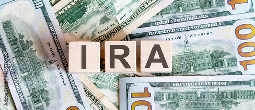 Concept words IRA on wooden blocks on a beautiful background from dollar bills. photo