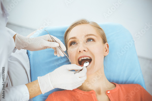 Happy smiling woman is being examined by dentist at dental clinic. Healthy teeth and medicine, stomatology concept