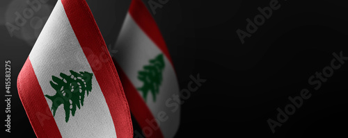 Small national flags of the Lebanon on a dark background