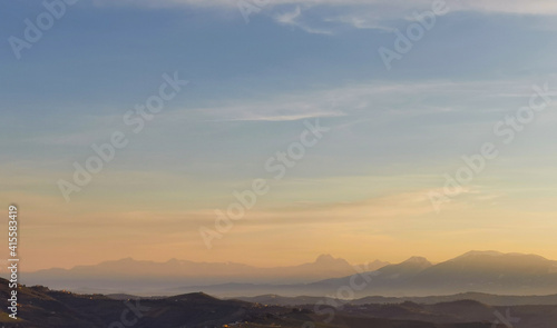 Montagne e valli dell’Appennino in un tramonto di luce e foschia azzurro e arancio