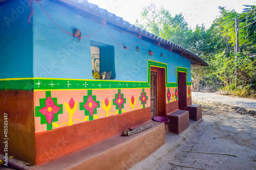 Rural Indian village hut at Purulia West Bengal with the view of unknown tribal hand painting on wall  and the unpaved road.