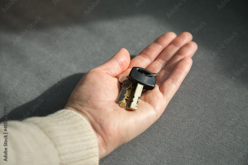 Fototapeta premium Close up shot of keys on a woman's palm. The concept of property, real estate and buying property