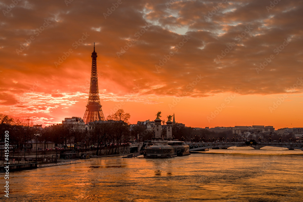 Obraz premium Paris, France - February 12, 2021: CItyscape of Paris in winter. Ships and brigde over Seine river with Eiffel tower in background and dramatic cloudy sky