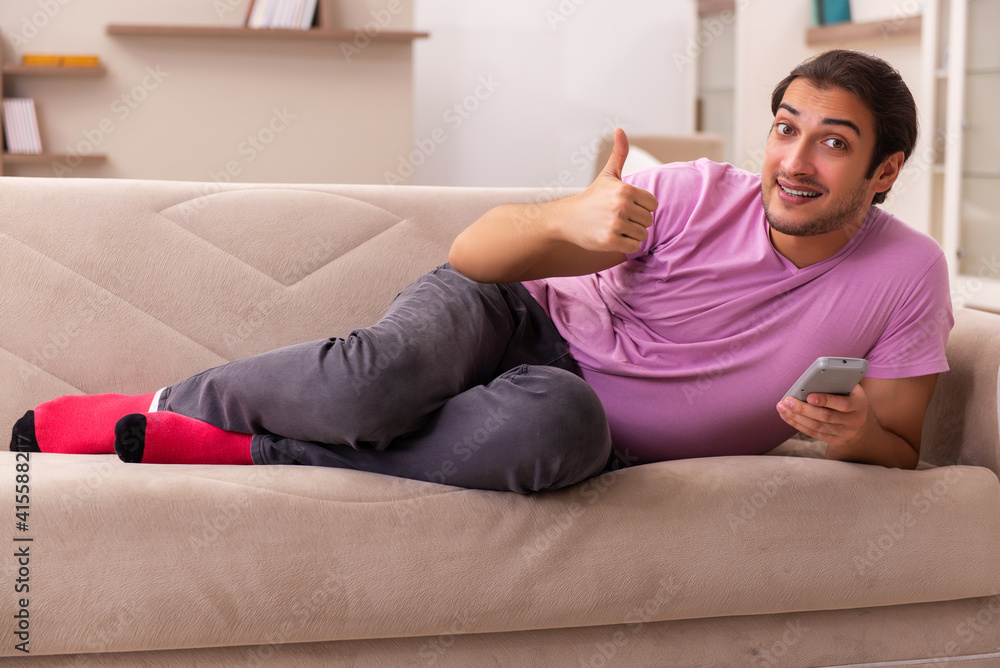 Young man watching tv at home during pandemic Young man watching tv at home during pandemic