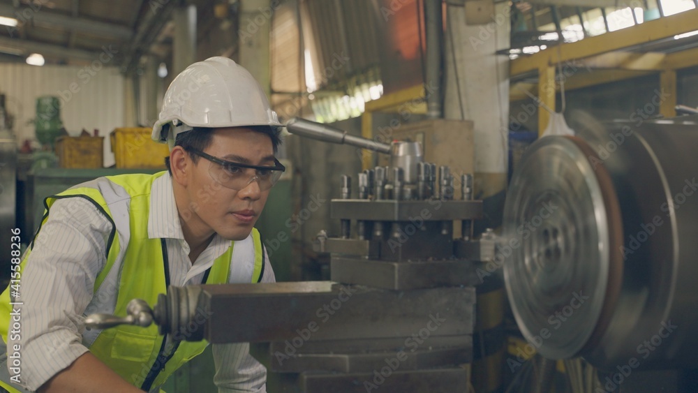 Asian engineer wear personal protective equipment, Manufacturing worker. Asian mechanical engineer operating industrial lathe machine. Engineering and industrial concept. Asian engineer wear personal protective equipment, Manufacturing worker. Asian mechanical engineer operating industrial lathe machine. Engineering and industrial concept.