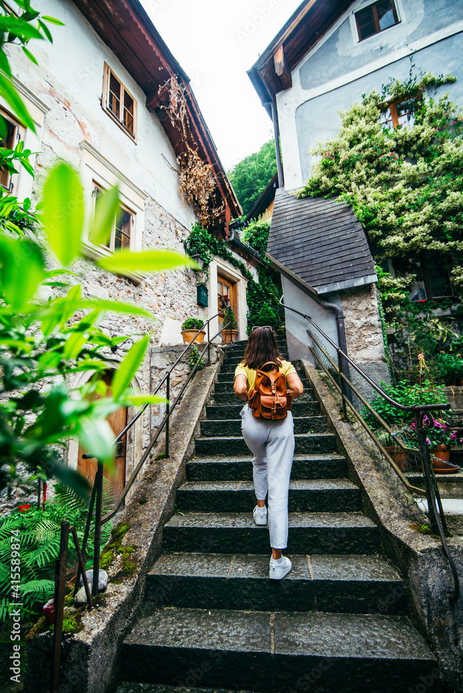 young adult female tourist walking by hallstatt city stone stairs