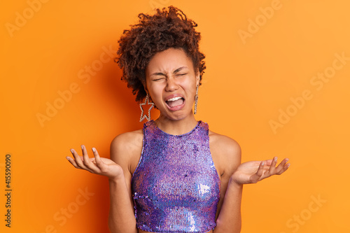 Obraz na plátně Displeased dark skinned curly young woman spreads palms feels frustrated cries a