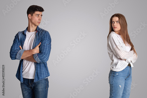 Offended young male and female with crossed arms turned away and looking at each other