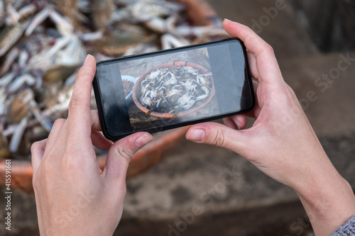 Canvas Print Cropped Hand Of Person Photographing Fishes In Mug With Mobile Phone