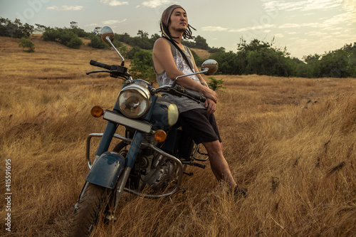 A man stands near a motorcycle in a field