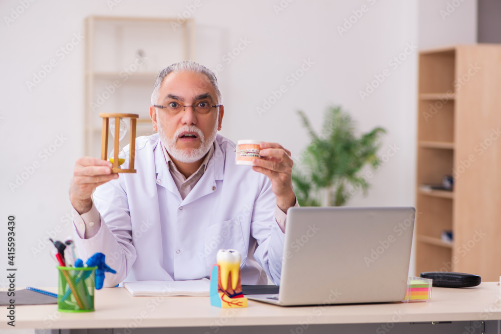 Old male dentist in time management concept Old male dentist in time management concept