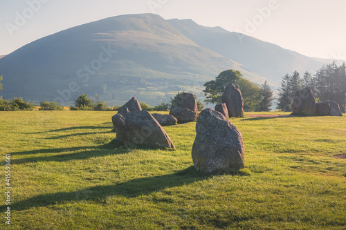 Платно Golden sunrise or sunset light cast across the historic and sacred megalithic site Castlerigg Stone Circle near Keswik, in the Lake District, Cumbria, England