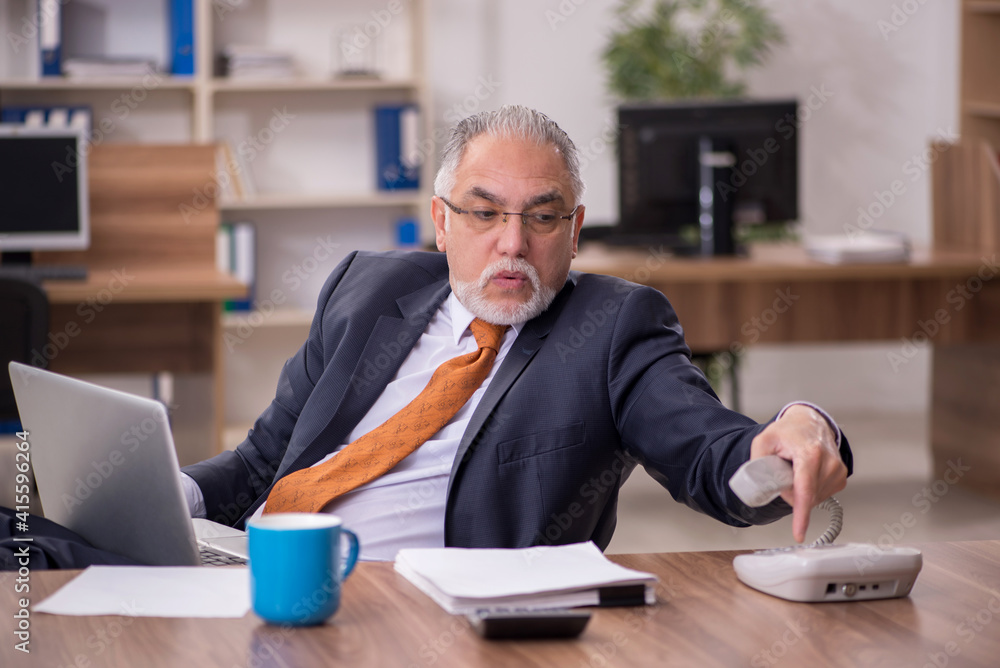 Old male employee working in the office Old male employee working in the office