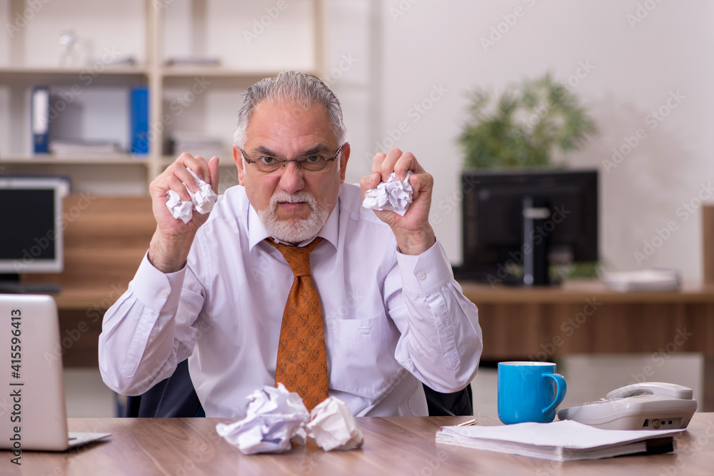 Old male employee in paper recycling concept Old male employee in paper recycling concept