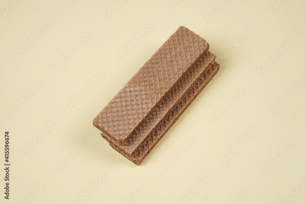 Random pile of wafers isolated on a yellow background. Chocolate biscuit wafers filled with delicious creamy chocolate. Dry and crispy wafers ready to eat. Ready to start the day with a wafer. Random pile of wafers isolated on a yellow background. Chocolate biscuit wafers filled with delicious creamy chocolate. Dry and crispy wafers ready to eat. Ready to start the day with a wafer.