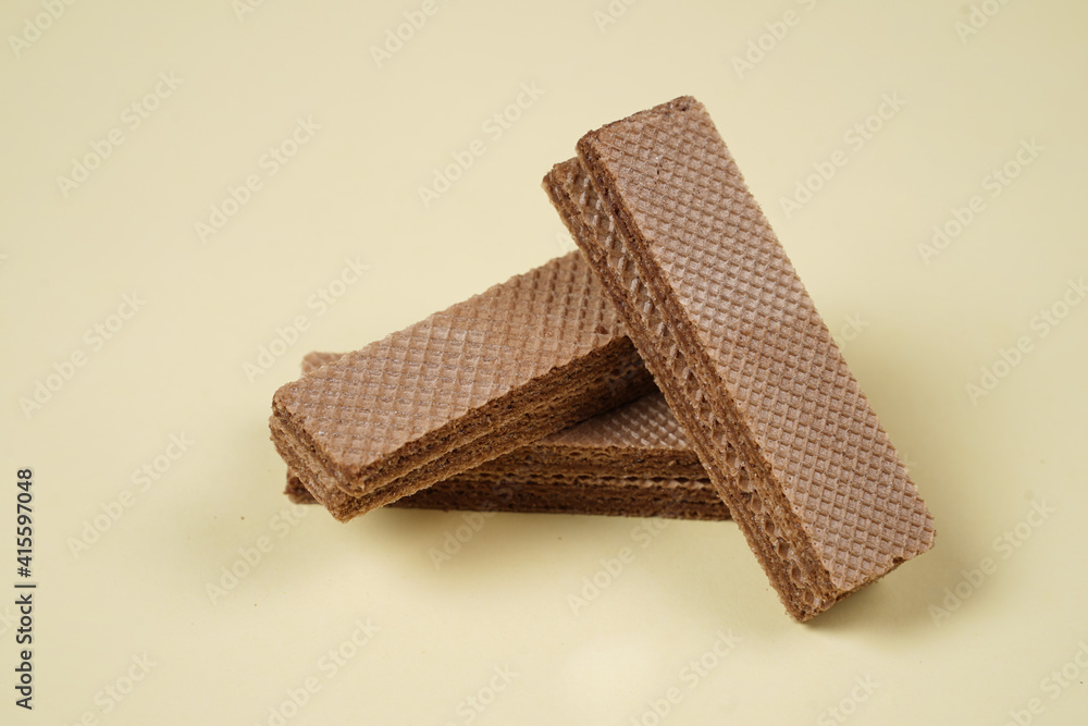 Random pile of wafers isolated on a yellow background. Chocolate biscuit wafers filled with delicious creamy chocolate. Dry and crispy wafers ready to eat. Ready to start the day with a wafer. Random pile of wafers isolated on a yellow background. Chocolate biscuit wafers filled with delicious creamy chocolate. Dry and crispy wafers ready to eat. Ready to start the day with a wafer.