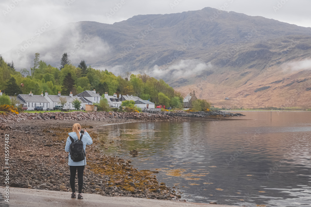 A young female tourist takes a photograph with her smartphone of Inverie village on the remote Knoydart peninsula in the Scottish Highlands, west coast of Scotland. A young female tourist takes a photograph with her smartphone of Inverie village on the remote Knoydart peninsula in the Scottish Highlands, west coast of Scotland.
