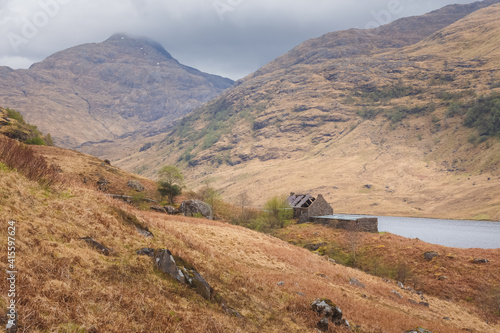 An isolated old stone bothy in a moody mountain landscape on the remote and rugged Knoydart peninsula in the Scottish Highlands, west coast Scotland.