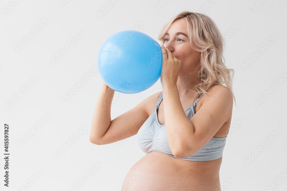 A beautiful young pregnant woman with a big belly in blue jeans holds a balloon that means that a boy will be born. A beautiful young pregnant woman with a big belly in blue jeans holds a balloon that means that a boy will be born.
