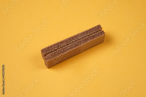 Random pile of wafers isolated on a yellow background. Chocolate biscuit wafers filled with delicious creamy chocolate. Dry and crispy wafers ready to eat. Ready to start the day with a wafer.