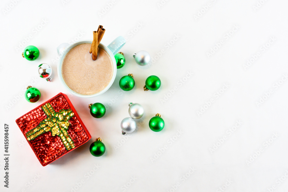 Hot chocolate in teal mug with Christmas ornaments on a white background