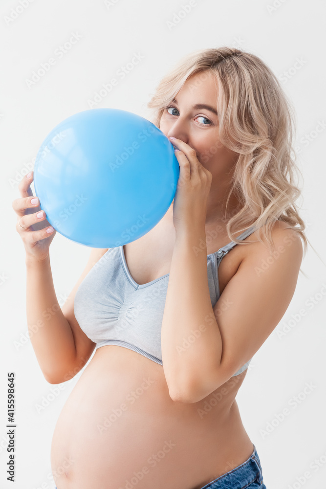 A beautiful young pregnant woman with a big belly in blue jeans holds a balloon that means that a boy will be born. A beautiful young pregnant woman with a big belly in blue jeans holds a balloon that means that a boy will be born.