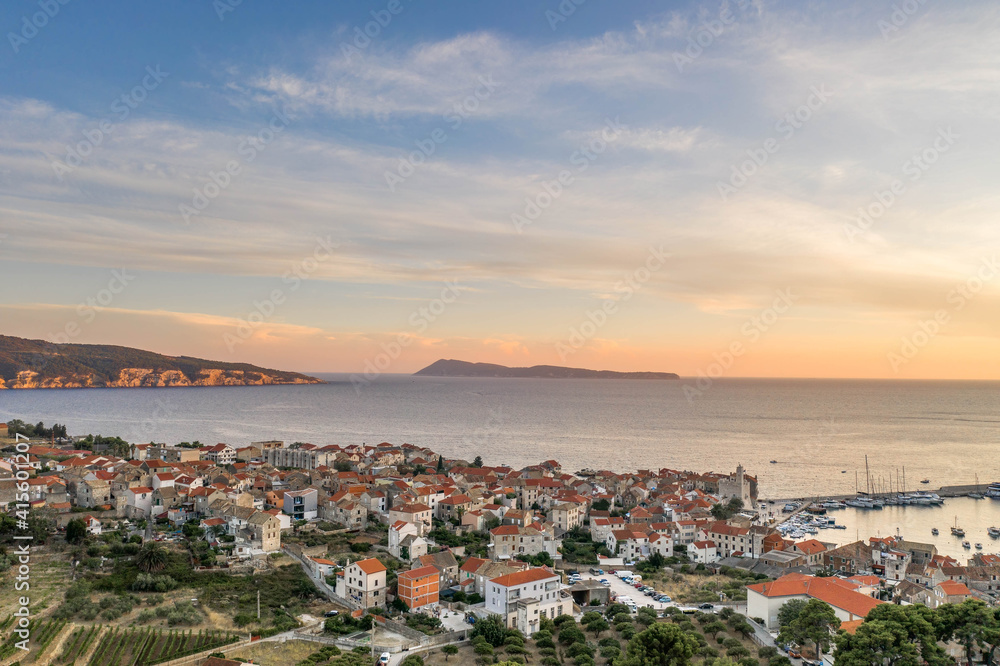 Aerial drone shot of Komiza village on Vis Island in Croatia during sunset with view of Bisevo island in summer