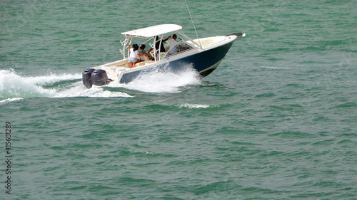 Blue and white motor boat powered by two outboard engines speeding on the Florida intra-Coastal Waterway.