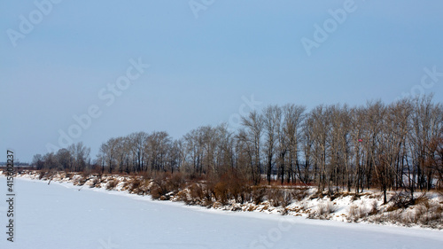 Picturesque Russian winter view of an unfrozen river with trees. Bright blue sky. Fantastic winter view © Екатерина Сергеева